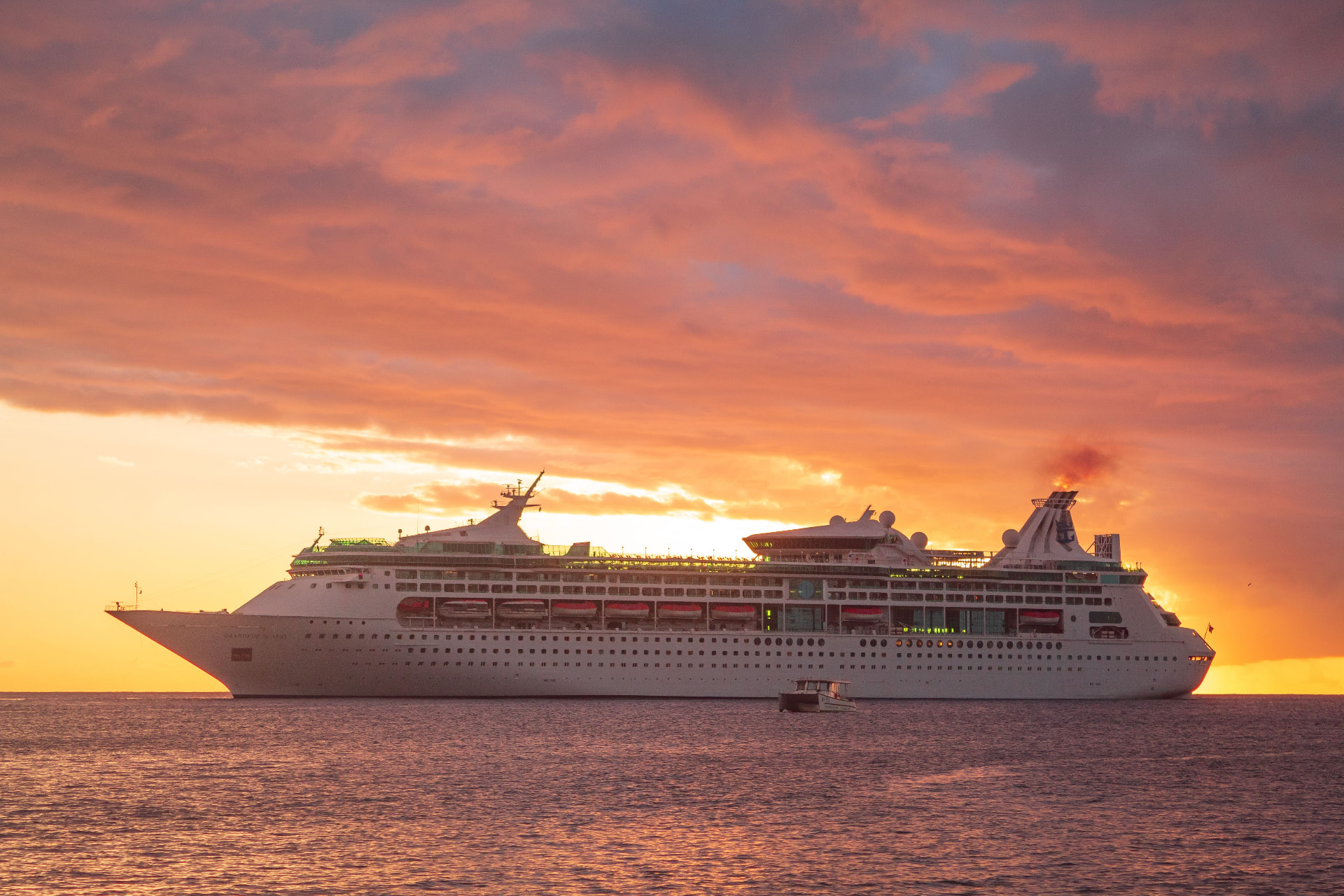 Cruise ship sailing past the coastline at sunset