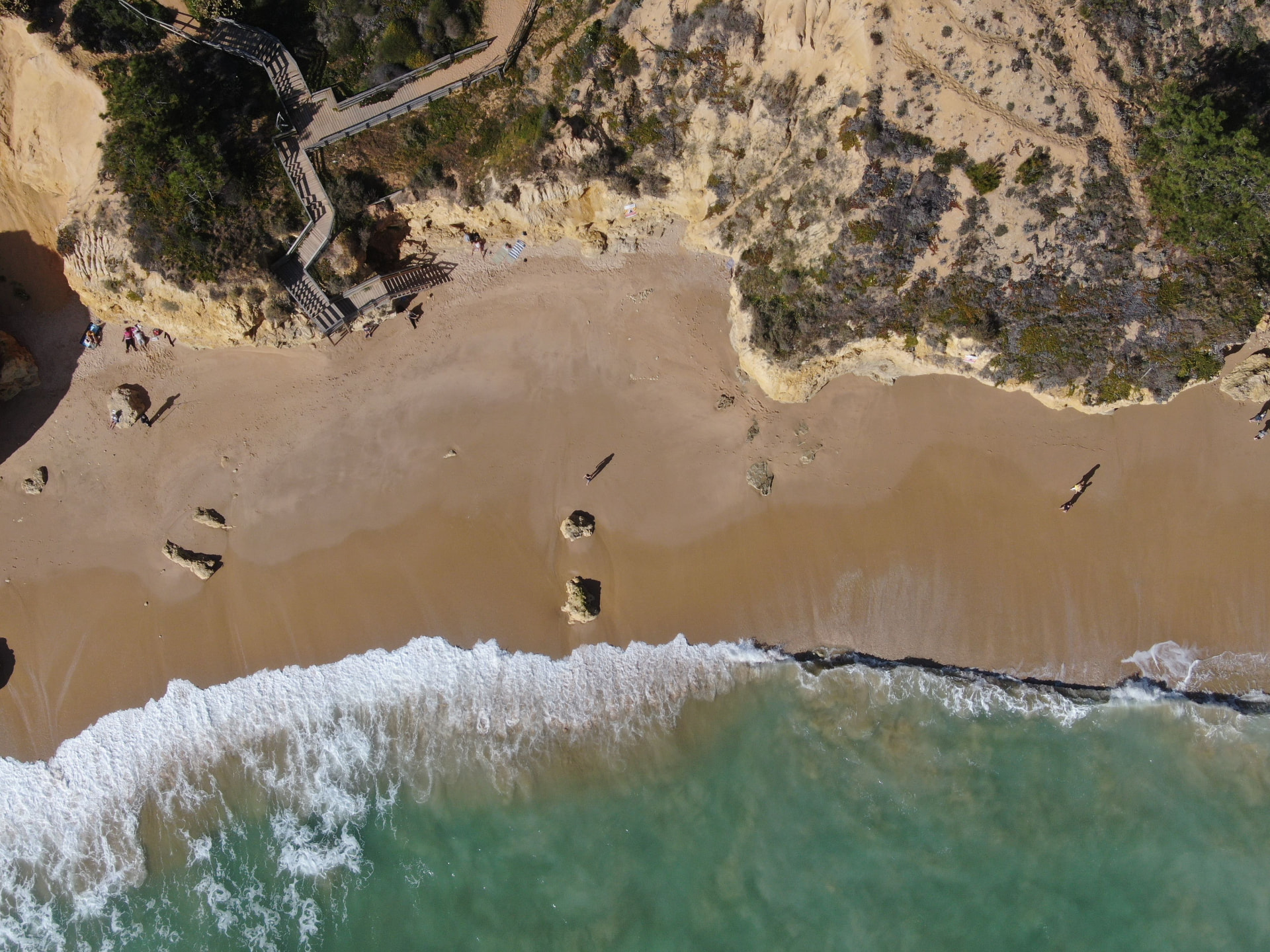 Aerial view of a sandy beach meeting clear turquoise water